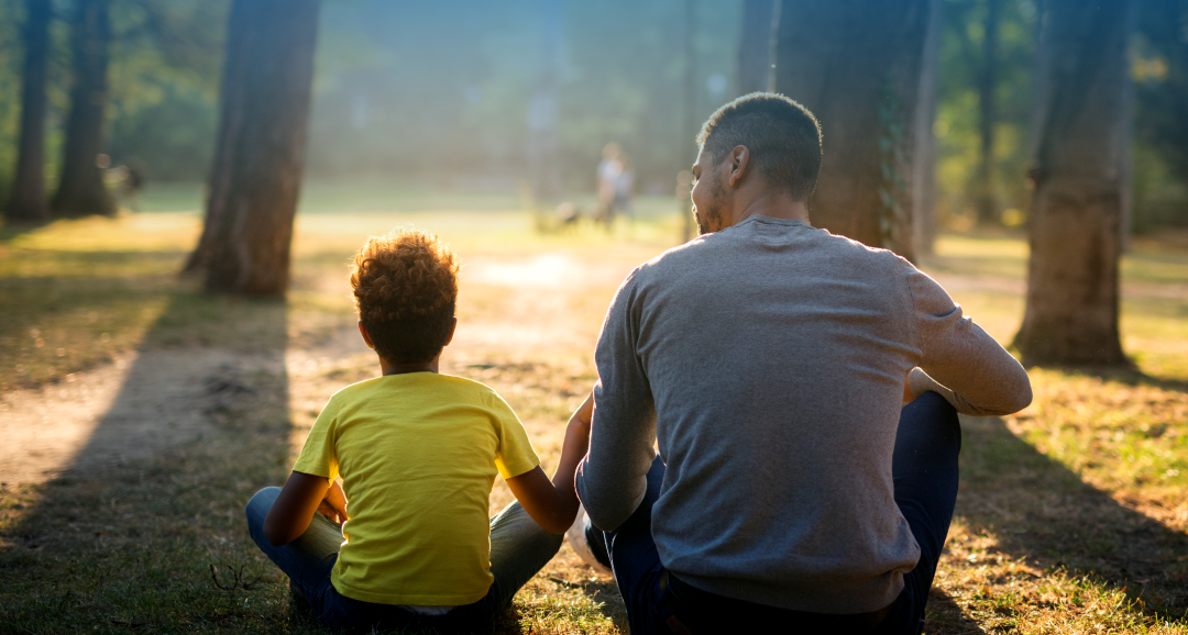 Pai e filho sentados juntos em um parque, representando presença, recomeço e reconstrução familiar