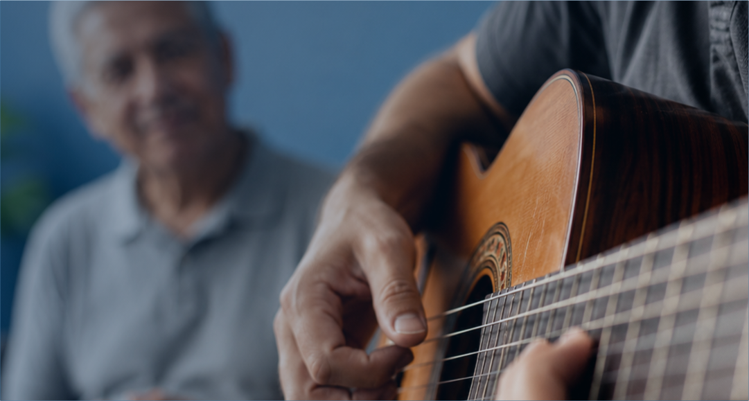 Profissional tocando violão durante atividade de musicoterapia com paciente